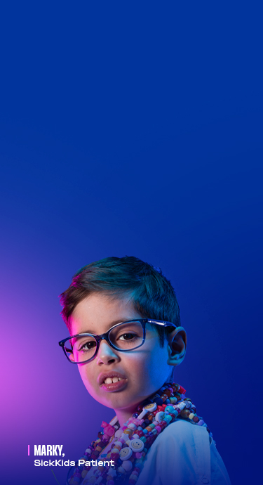 Marky, SickKids patient, wearing a hospital gown and several strands of bravery beads.