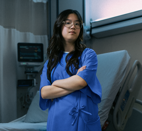 Audrey at SickKids, standing in a hospital room with her arms crossed.