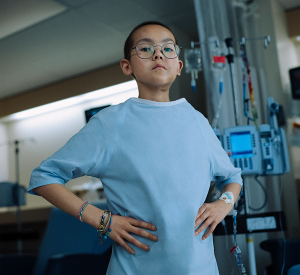 Chloe standing with her hands on her hips at SickKids. There’s an IV pole in the background.