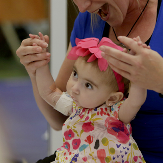 SickKids patient with staff member and hands in the air
