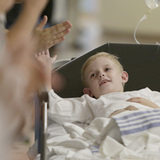 SickKids patient in bed giving high five